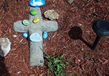 a concrete cross with colored rocks around it and a battery powered light